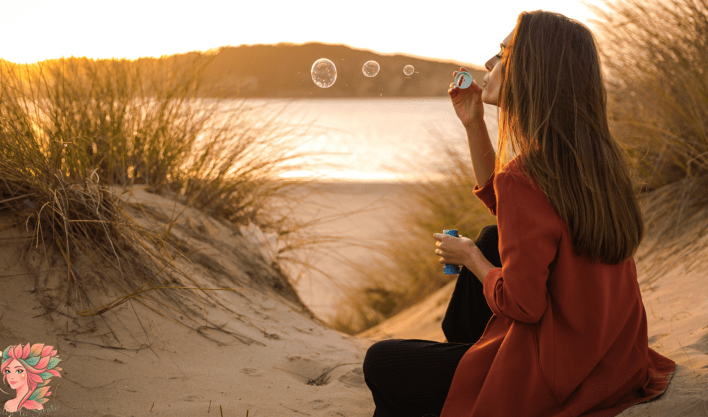 Femme assise au coucher du soleil soufflant des bulles, symbolisant les fluctuations naturelles de la libido, de l’humeur et de l’énergie selon le cycle féminin.