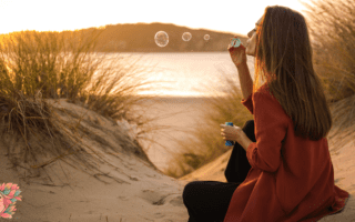 Femme assise au coucher du soleil soufflant des bulles, symbolisant les fluctuations naturelles de la libido, de l’humeur et de l’énergie selon le cycle féminin.