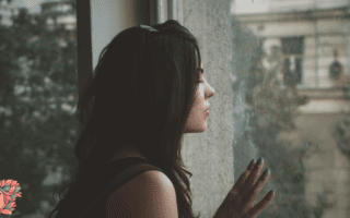 Femme fatiguée regardant par la fenêtre, illustrant les pics de glycémie et la fatigue après les repas