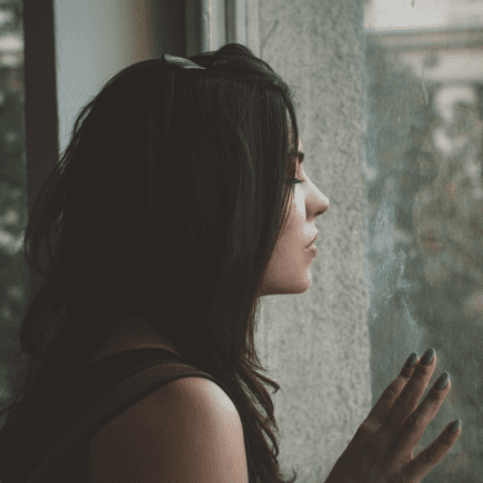 Femme fatiguée regardant par la fenêtre, illustrant les pics de glycémie et la fatigue après les repas