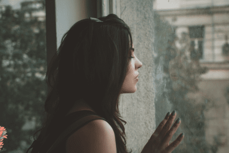 Femme fatiguée regardant par la fenêtre, illustrant les pics de glycémie et la fatigue après les repas