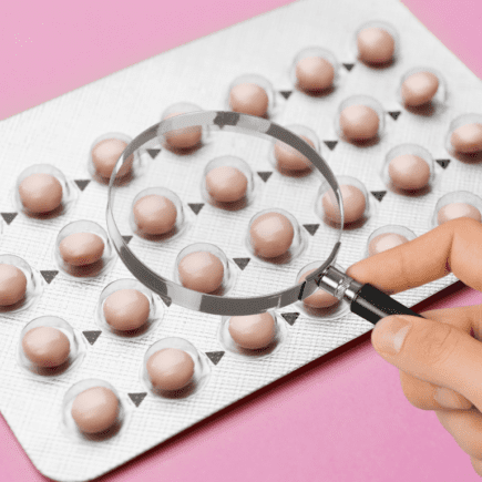 Plaquette de pilule examinée à la loupe, symbolisant l’analyse des effets secondaires et des risques hormonaux