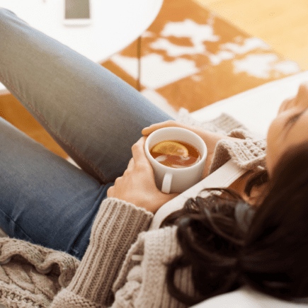 Femme se reposant avec une boisson chaude illustrant l’impact du cycle menstruel sur la glycémie et les hormones