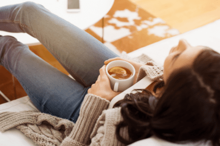 Femme se reposant avec une boisson chaude illustrant l’impact du cycle menstruel sur la glycémie et les hormones